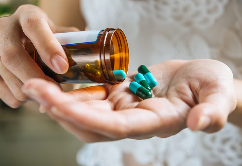 Woman's hand pours the medicine pills out of the bottle